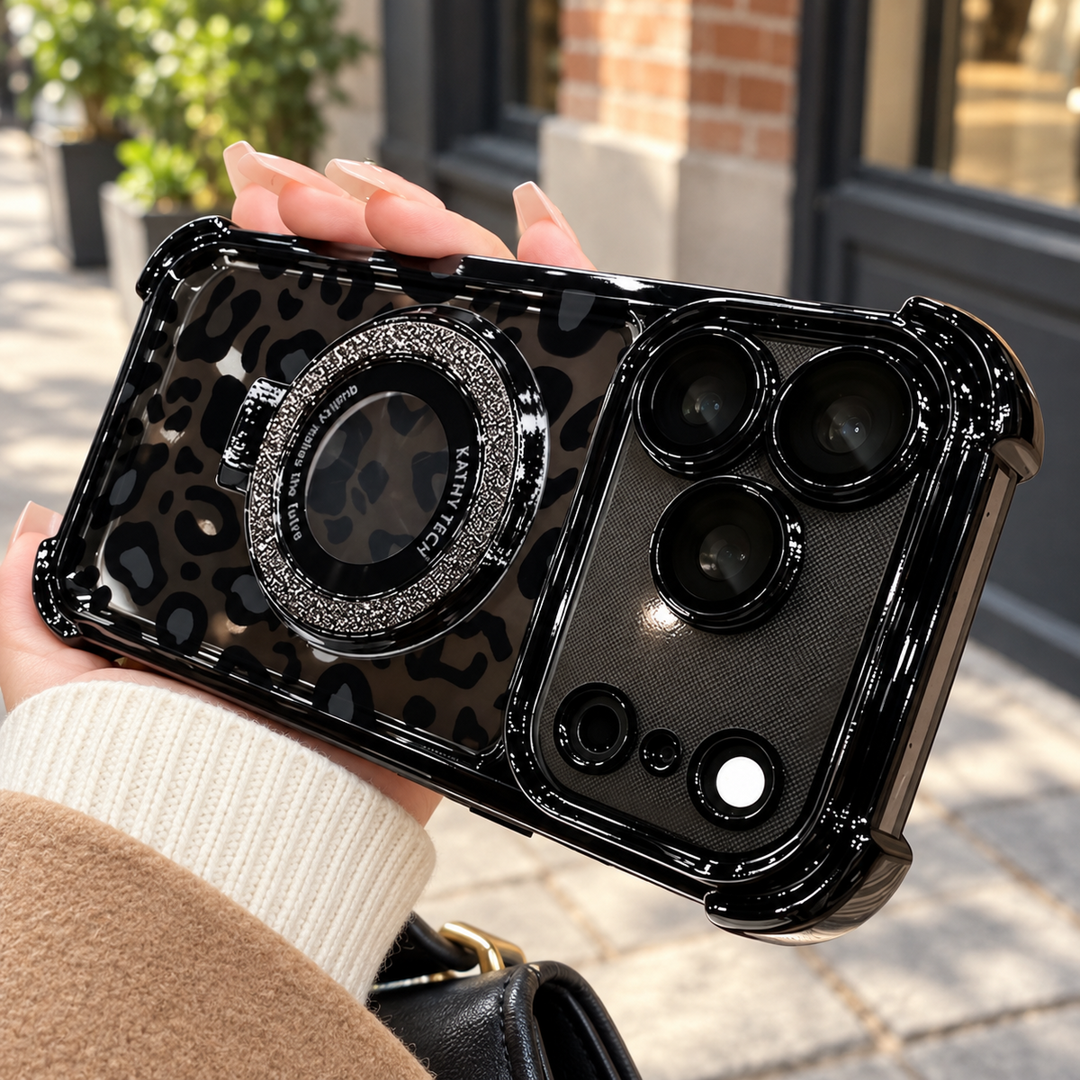 Black leopard case showing the glossy frame, reinforced corners and glitter ring in a street setting