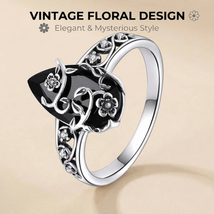 Black teardrop ring with silver-tone flowers and curling vines