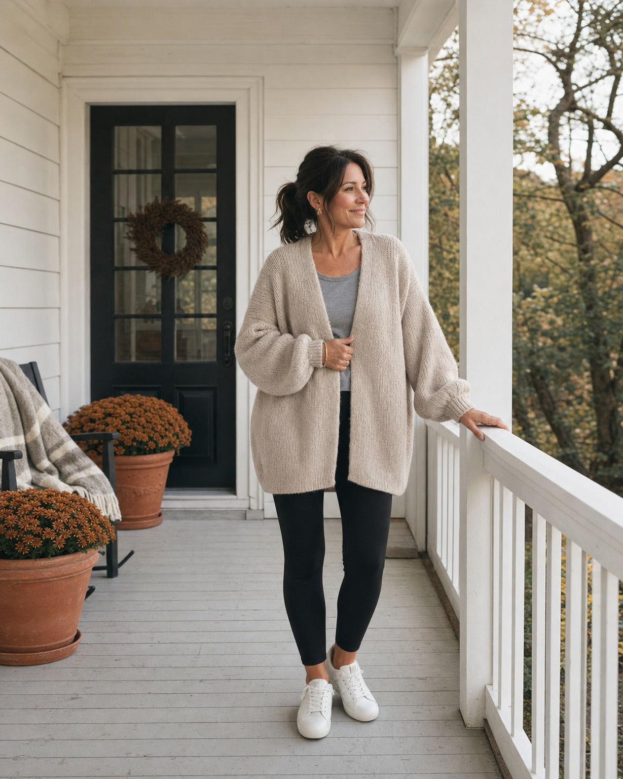 Woman in the oatmeal cardigan and black leggings on an autumn front porch