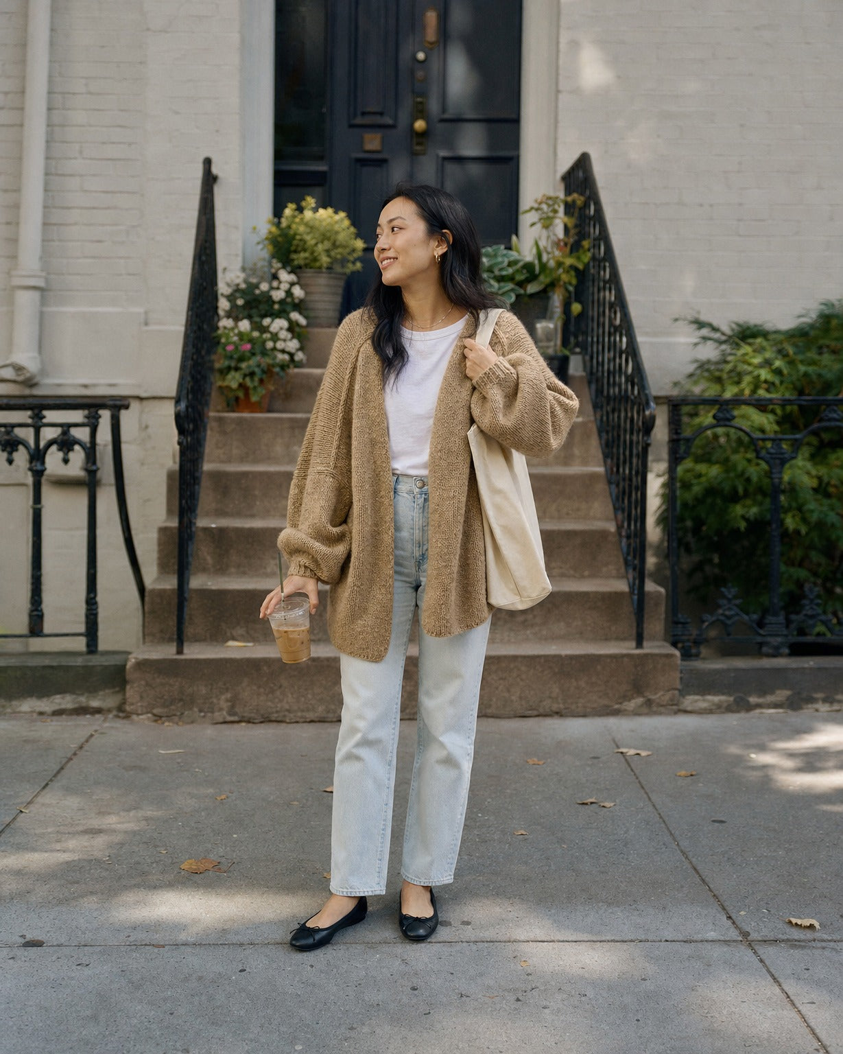 Petite woman wearing the camel cardigan in size S on brownstone steps